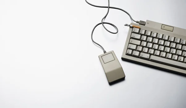 top view of keyboard with a cigar and mouse apple mac computer from the 80s on light gray background