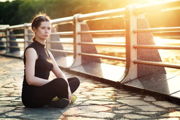 Ung smal och stark kvinna mediterar i parken sommaren på solnedgången — Stockfoto