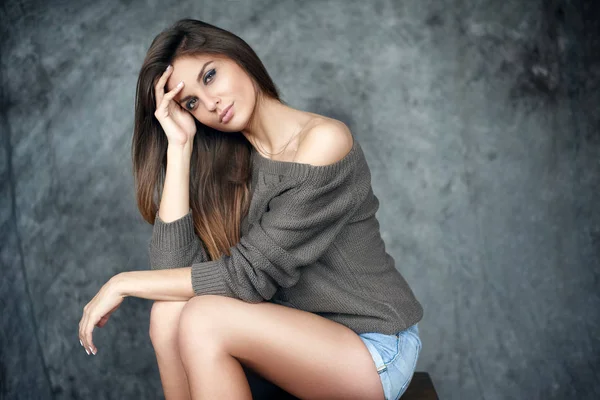 Portrait of a beautiful young and sexy girl in a sweater and denim shorts — Stock Photo, Image