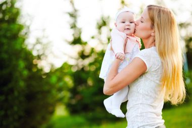 Genç anne yürüme parkta yaz aylarında bebeği ile. Aile ve sağlıklı yaşam kavramı