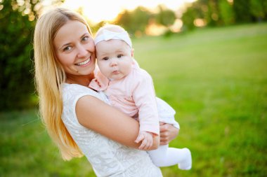 Genç anne yürüme parkta yaz aylarında bebeği ile. Aile ve sağlıklı yaşam kavramı
