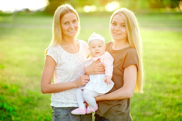 Two young mothers are walking in the park in summer with her baby. LGBT Lesbian Couple. The concept of  family and healthy lifestyle — Stock Photo, Image