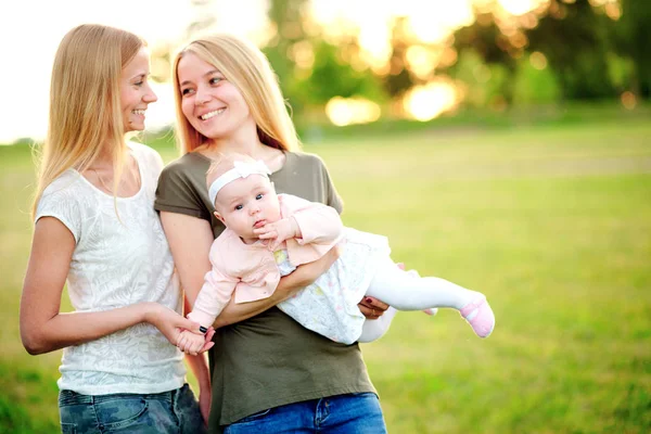 Two young mothers are walking in the park in summer with her baby. LGBT Lesbian Couple. The concept of  family and healthy lifestyle — Stock Photo, Image