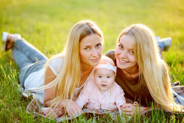 Two young mothers are walking in the park in summer with her baby. LGBT Lesbian Couple. The concept of  family and healthy lifestyle — Stock Photo, Image