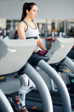 Güçlü genç ve güzel kadın spor salonunda koşu bandı üzerinde çalışır. Kavramı bir sağlıklı yaşam ve spor