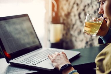 Genç adam bilgisayarda çalışan ve çay içme bir kafede. Teknoloji ve yaşam tarzı kavramı