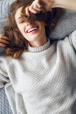 Bir yaşam tarzı kavramı. Bir yatak ve gülüyor bir kazaklı genç güzel seksi kız yatıyor