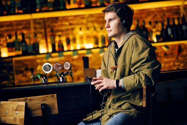 Man listening to music on headphones at the bar