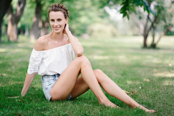 Hermosa chica sexy en pantalones cortos descansando en un parque en la hierba — Foto de Stock