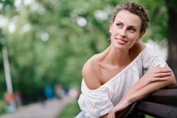 Çiller ve yaz aylarında bir parkta bankta sağlıklı bir kar-beyaz gülümseme ile güzel bir genç kız portresi — Stok fotoğraf