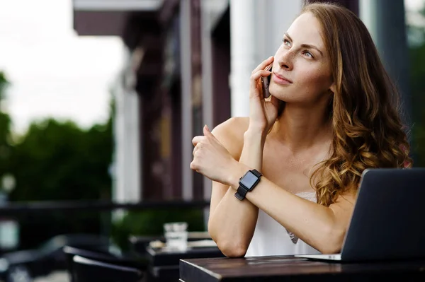 Hermosa chica hablando por teléfono en un café de verano — Foto de Stock