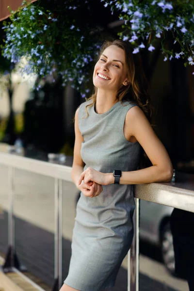 Joven y hermosa chica de pie cerca de la terraza con flores y sonriendo — Foto de Stock