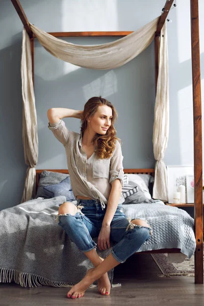 Begreppet en livsstil. Vacker flicka sitter på sängen hemma — Stockfoto