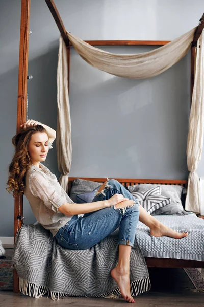 Begreppet en livsstil. Vacker flicka sitter på sängen hemma — Stockfoto