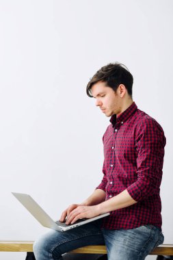 Ofis masasında oturan dizüstü bilgisayarda çalışan adam. Genç adam kararlı. Başarılı bir kişi kavramı