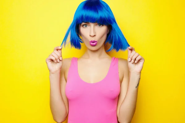 Menina sexy bonita em peruca azul e maiô rosa está se divertindo e brincando no fundo amarelo — Fotografia de Stock