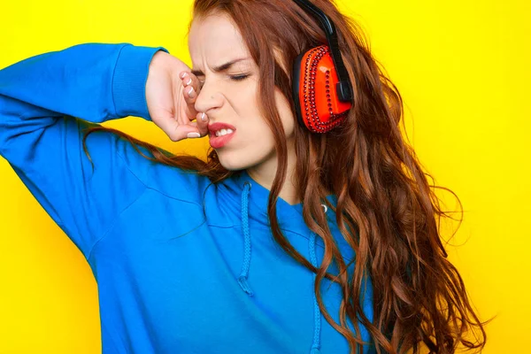 年轻漂亮性感的女孩 Dj 在蓝色夹克在黄色的背景和有乐趣的红色耳机听音乐 — 图库照片