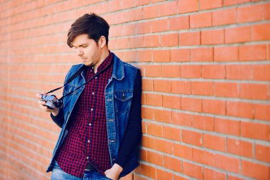 Genç ve yakışıklı adam bir tuğla duvar tarafından standları ve fotoğraflar üzerinde bir aynasızlar kamera çekiyor