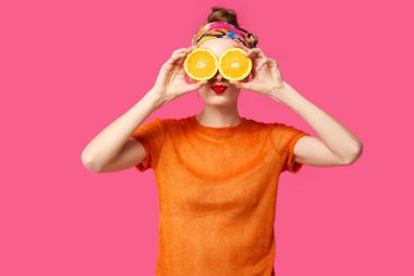 Pembe bir arka plan üzerinde genç kadın bir kesik elleri ve gülüyor turuncu tutar. Renk obsesyon kavramı. Minimalist tarzı. Şık Trendy