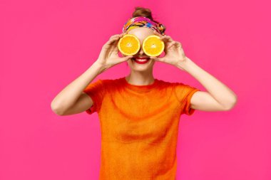 Pembe bir arka plan üzerinde genç kadın bir kesik elleri ve gülüyor turuncu tutar. Renk obsesyon kavramı. Minimalist tarzı. Şık Trendy