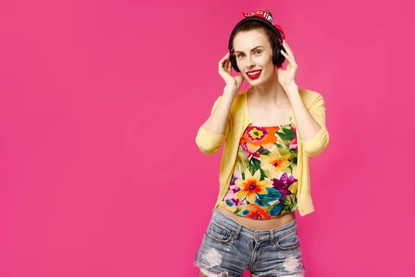 Menina ouvindo música em fones de ouvido sem fio em um fundo rosa e sorrindo. Conceito de obsessão a cores. Estilo minimalista. Elegante moda — Fotografia de Stock