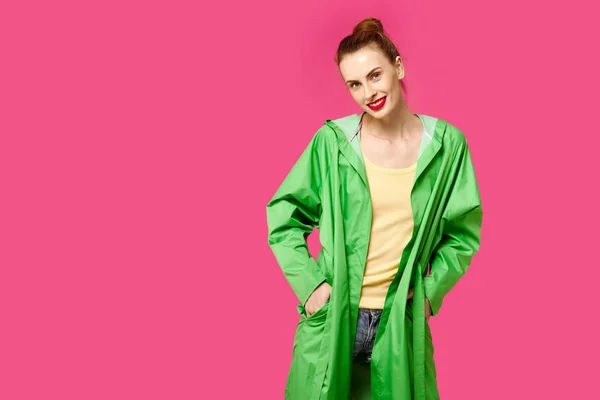 Mujer joven con un abrigo verde sobre un fondo rosa. Concepto de obsesión por el color. Estilo minimalista. Moda con estilo —  Fotos de Stock