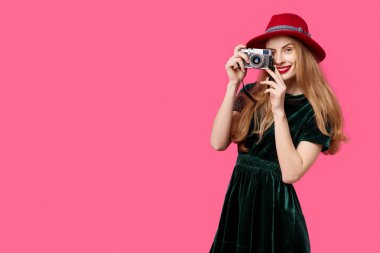 Yeşil elbise ve şapka pembe bir arka plan üzerinde genç güzel kadın nadir kamera ellerini ve gülümsüyor tutar. Sağlıklı beslenme ve spor kavramı. Renk obsesyon kavramı. Minimalist arpacık