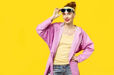 Genç kadın sarı bir arka plan ve pembe ceket ve güneş gözlüğü. Renk obsesyon kavramı. Minimalist tarzı. Şık Trendy