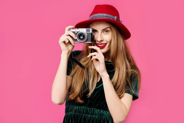 年轻美丽的女人在粉红色的背景, 绿色的礼服和帽子持有一个罕见的相机在她的手和微笑。健康营养和体育的概念。色彩痴迷的概念。简约猪圈 — 图库照片