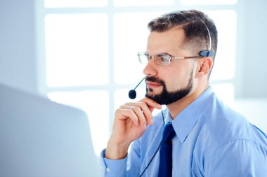 Ofiste kulaklık ve bilgisayarla çalışan yakışıklı bir destekçi.