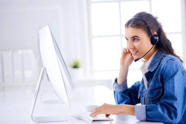 Ofiste bilgisayarla çalışan gülümseyen kadın müşteri hizmetleri operatörü