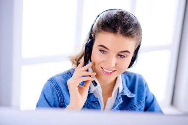 Ofiste bilgisayarla çalışan gülümseyen kadın müşteri hizmetleri operatörü