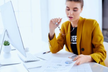 İş kadını belgeleri okuyor ve ofisteki masada oturuyor. 