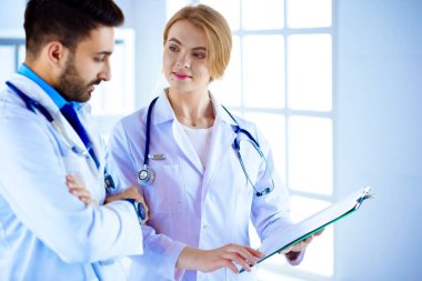 İki melez doktor bir dosya tutuyor ve hastalardan bahsediyorlar.