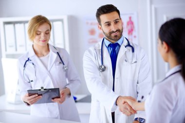 Hastanedeki bir grup genç doktor iletişim kurup el sıkışıyor.