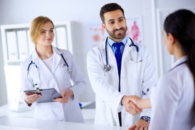 Genç doktor hastanede bir hemşireyle tokalaşıyor. İnsan vücudunun arka planına karşı