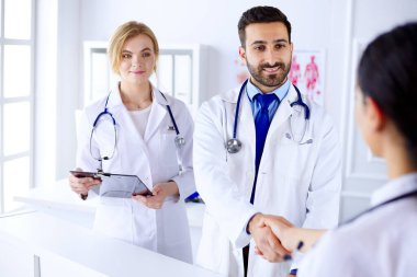 Genç Arap doktor hastanede bir hemşireyle tokalaşıyor. İnsan vücudunun arka planına karşı
