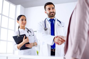 Genç Arap doktor hastanede bir hastayla el sıkışıyor.