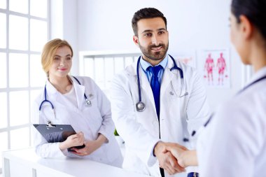 Genç Arap doktor hastanede bir hemşireyle tokalaşıyor. İnsan vücudunun arka planına karşı