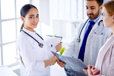 İki doktor bir hastayla iletişim kuruyor ve bir hastaya röntgen filmi gösteriyor.