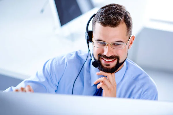Handsome support man smiling and working with headset and computer in office
