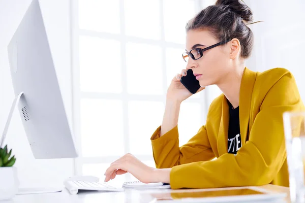 Jovem Mulher Negócios Falando Telefone Enquanto Estiver Usando Desktop — Fotografia de Stock