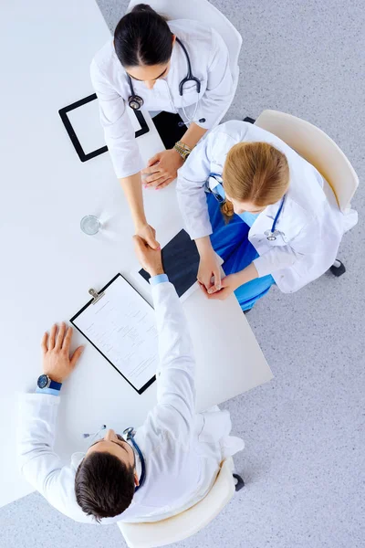 Professional doctors handshaking at hospital. Flat lay, top view.  Group of doctors at hospital