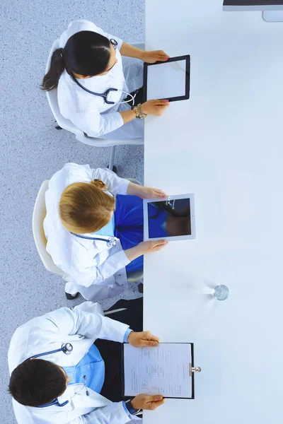 Group of doctors sitting in he office with gadgets and tablets in hospital , top view