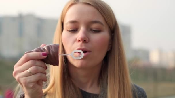Молода жінка дме мильні бульбашки на відкритому повітрі. Близький погляд. 4k — стокове відео