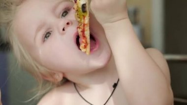 Küçük kız evde pizza yiyor.