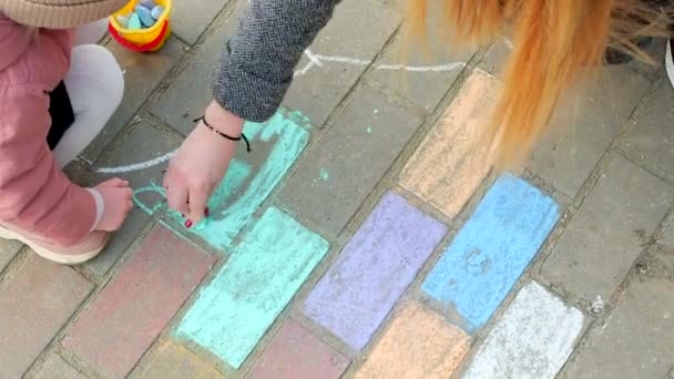 Woman with a child is painting. Daughter and mother are painting with chalk outdoors — Stock Video