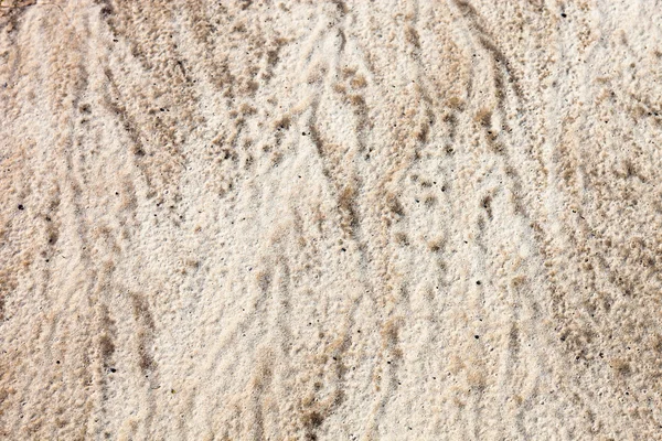 Sand surface after the rain with the visible traces of the raindrops and water currents