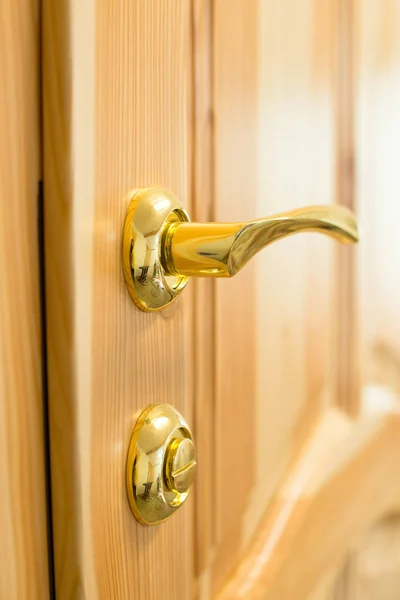 Golden door handle and lock on the wooden door