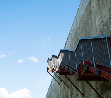 Gri beton duvardaki metal merdivenler.